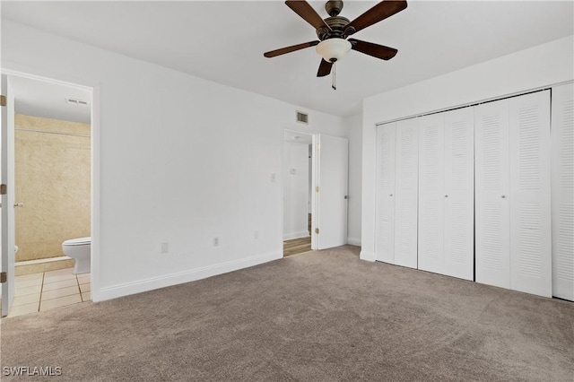 unfurnished bedroom with ceiling fan, ensuite bathroom, carpet floors, and a closet