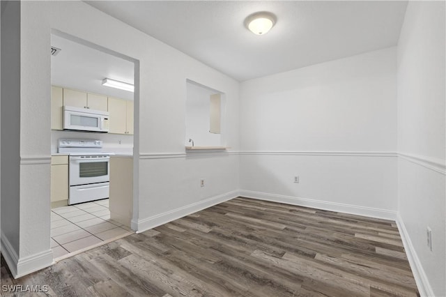 kitchen with light hardwood / wood-style floors, white appliances, and cream cabinetry