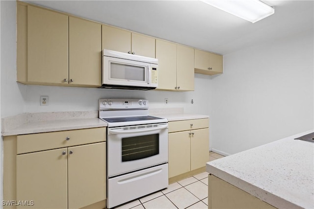 kitchen featuring light tile patterned floors, white appliances, and cream cabinetry