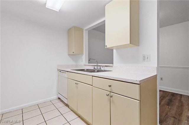 kitchen with light tile patterned flooring, cream cabinets, sink, and white dishwasher