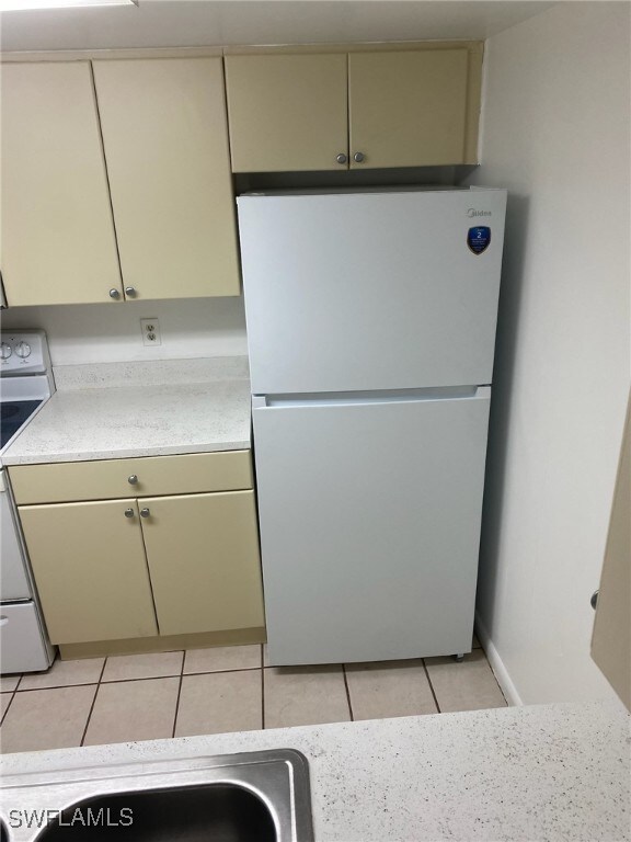 12658 Kenwood Ln Unit D, Fort Myers, FL 33907 - kitchen featuring freestanding refrigerator, range, light tile patterned floors, light countertops, and cream cabinetry