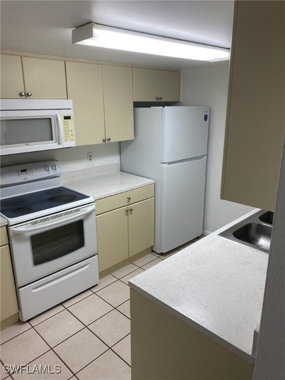 12658 Kenwood Ln Unit D, Fort Myers, FL 33907 - kitchen featuring white appliances, cream cabinetry, a sink, light countertops, and light tile patterned flooring