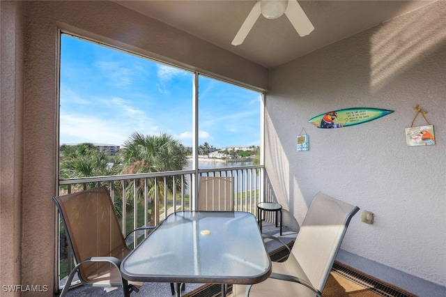 sunroom / solarium with ceiling fan and a water view