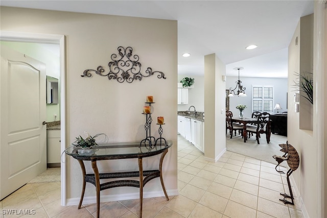 hall featuring sink, light tile patterned floors, and a chandelier