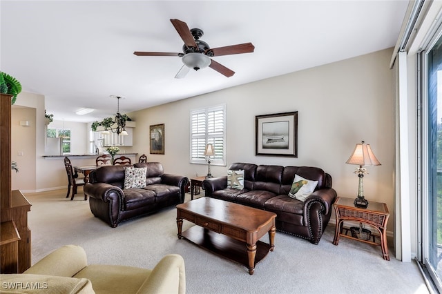 living room with ceiling fan, light colored carpet, and plenty of natural light