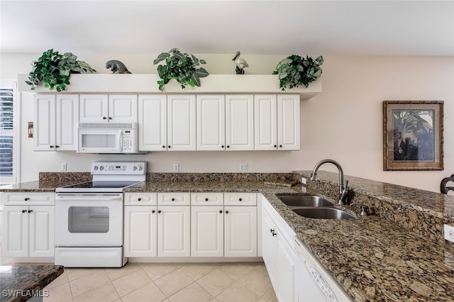 kitchen with sink, white appliances, white cabinets, light tile patterned flooring, and dark stone counters