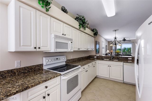 kitchen with sink, white appliances, white cabinetry, hanging light fixtures, and dark stone counters