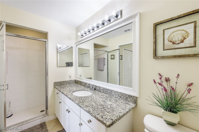 bathroom featuring tiled shower, vanity, toilet, and tile patterned flooring