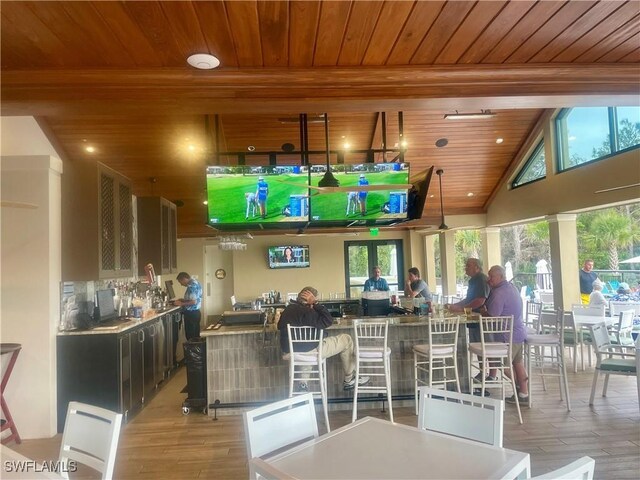 bar with plenty of natural light, light wood-type flooring, and wooden ceiling