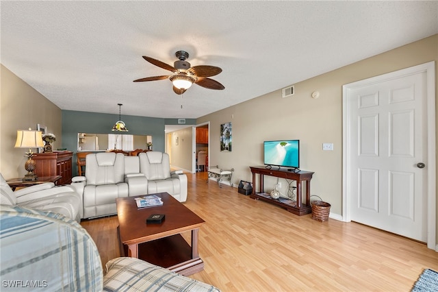 living room with ceiling fan, light hardwood / wood-style flooring, and a textured ceiling