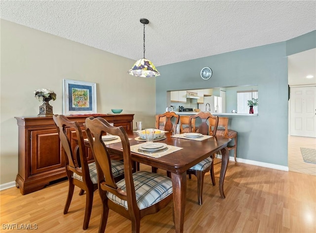 dining room featuring a textured ceiling and light wood-type flooring