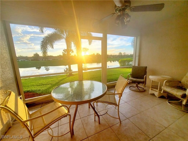 sunroom / solarium with ceiling fan and a water view