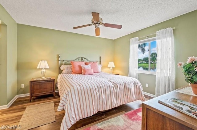 bedroom featuring hardwood / wood-style flooring, a textured ceiling, and ceiling fan