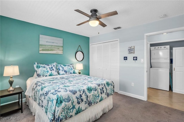 carpeted bedroom with stacked washer / drying machine, a closet, a textured ceiling, and ceiling fan