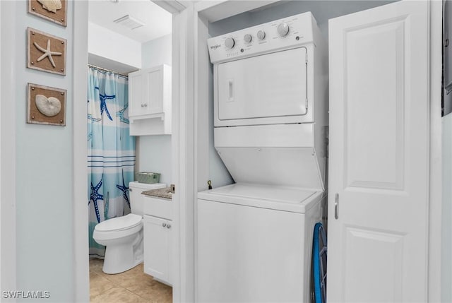 laundry area with light tile patterned floors and stacked washer and clothes dryer