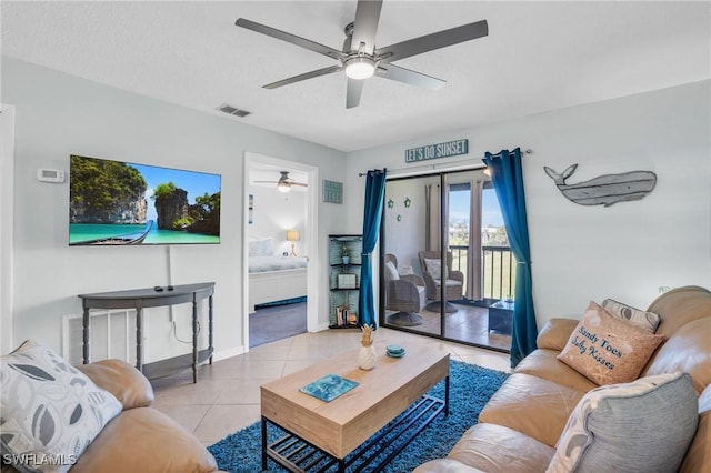 living room featuring ceiling fan, a textured ceiling, and light tile patterned floors