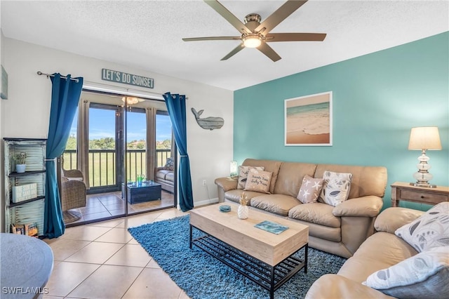 living room with ceiling fan, a textured ceiling, and light tile patterned flooring