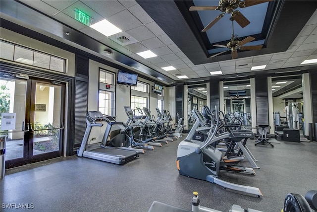 gym featuring a paneled ceiling, ceiling fan, and french doors