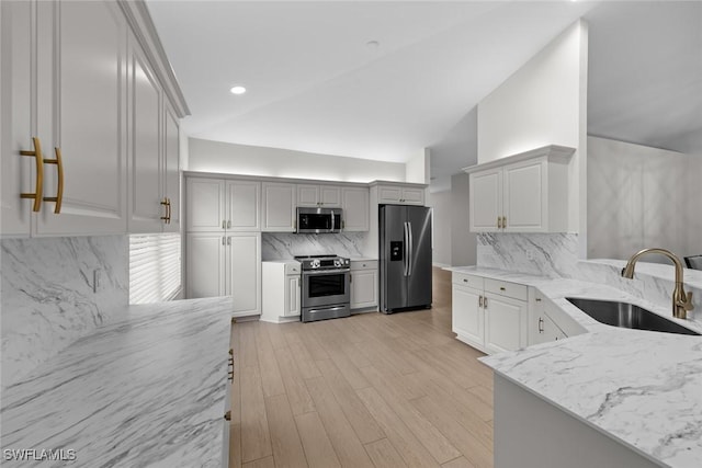 kitchen with lofted ceiling, stainless steel appliances, sink, and white cabinets