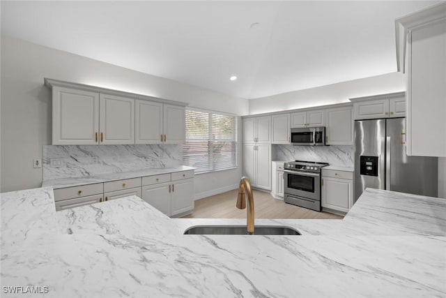 kitchen featuring lofted ceiling, sink, gray cabinetry, and appliances with stainless steel finishes