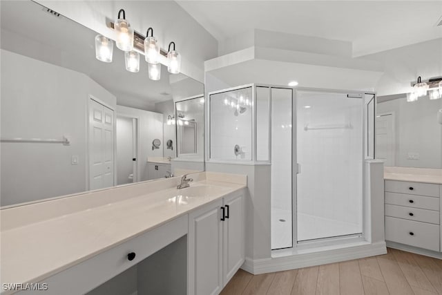 bathroom with vanity, a shower with shower door, and wood-type flooring