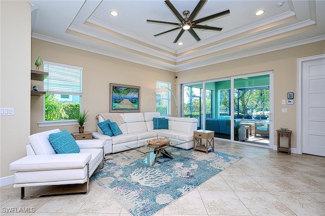 living room with a tray ceiling, crown molding, and ceiling fan