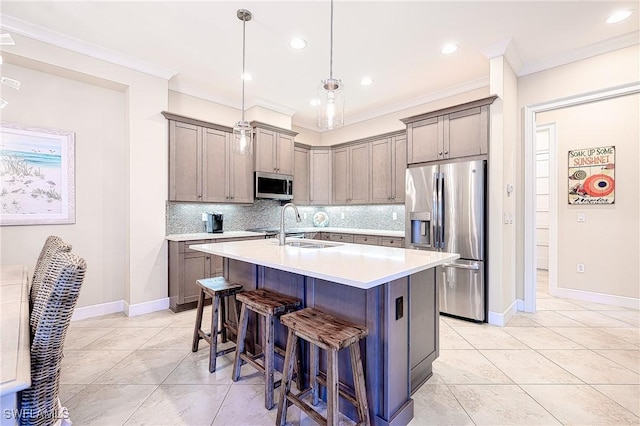 kitchen with a breakfast bar, decorative light fixtures, a center island with sink, appliances with stainless steel finishes, and backsplash