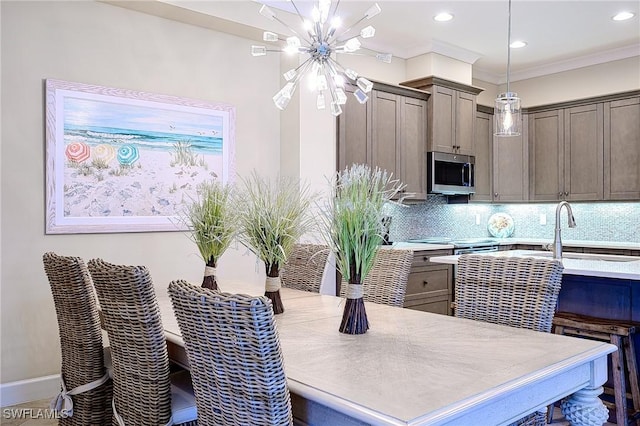 kitchen featuring sink, crown molding, an inviting chandelier, decorative backsplash, and decorative light fixtures