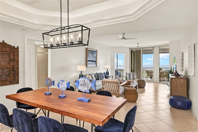 tiled dining room featuring ornamental molding, ceiling fan, and a tray ceiling