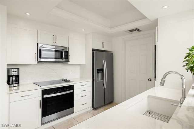 kitchen featuring stainless steel appliances, white cabinets, and a tray ceiling