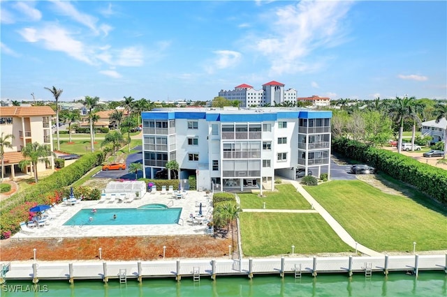 back of property with a water view, a community pool, a yard, and a patio