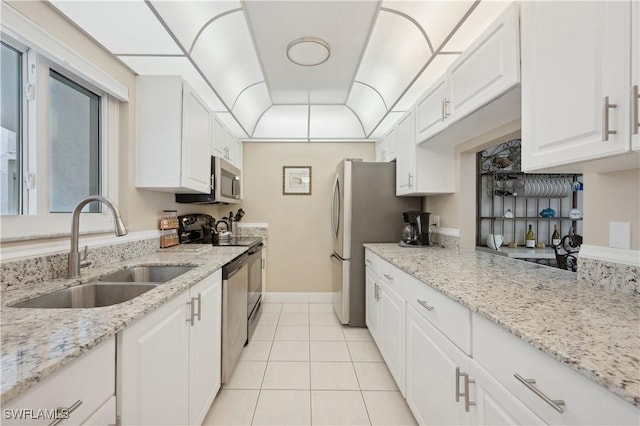 kitchen with appliances with stainless steel finishes, sink, white cabinets, light tile patterned floors, and light stone countertops