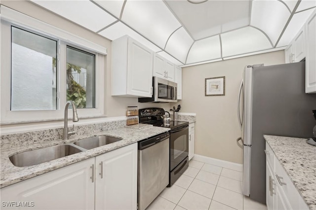 kitchen featuring sink, white cabinetry, light stone counters, light tile patterned floors, and appliances with stainless steel finishes