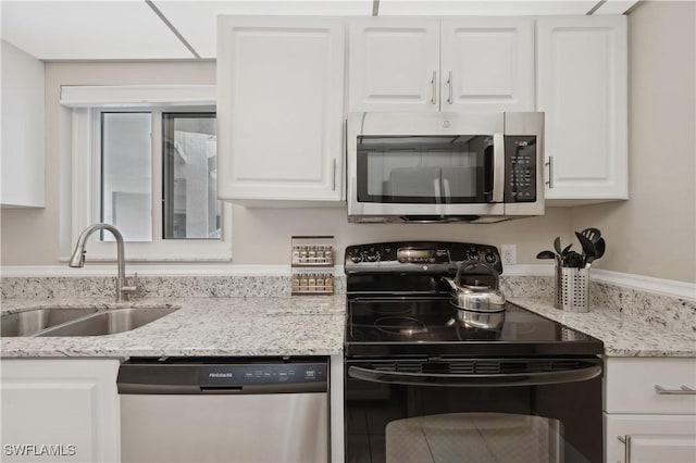 kitchen featuring stainless steel appliances, white cabinetry, light stone countertops, and sink