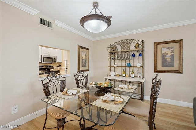 dining space with crown molding and light hardwood / wood-style flooring