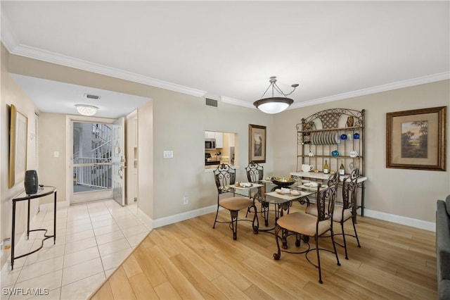 dining area with ornamental molding and light hardwood / wood-style flooring