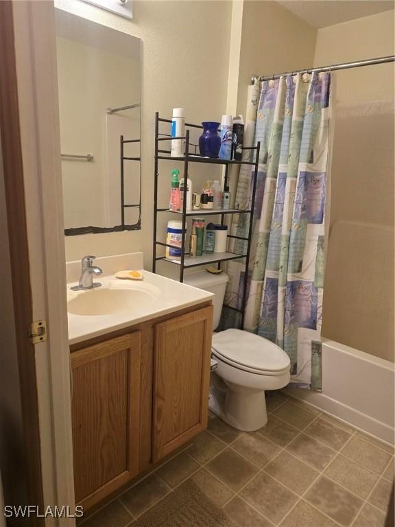 full bathroom with shower / tub combo with curtain, vanity, tile patterned floors, and toilet