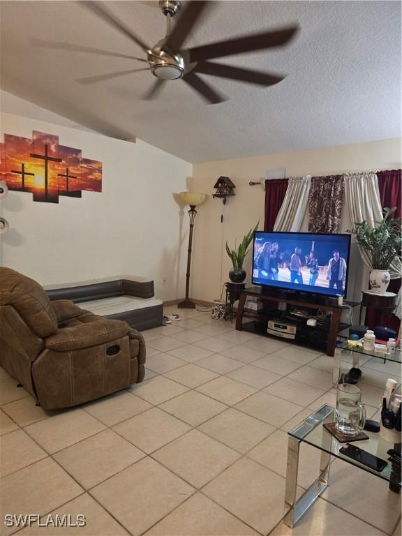 living room featuring vaulted ceiling, a textured ceiling, and light tile patterned floors