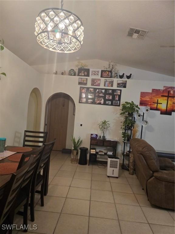 dining area featuring an inviting chandelier, vaulted ceiling, and light tile patterned floors