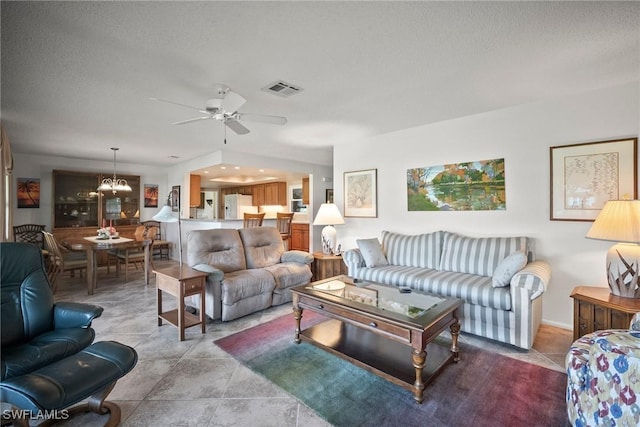 living room with light tile patterned flooring, ceiling fan with notable chandelier, and a textured ceiling