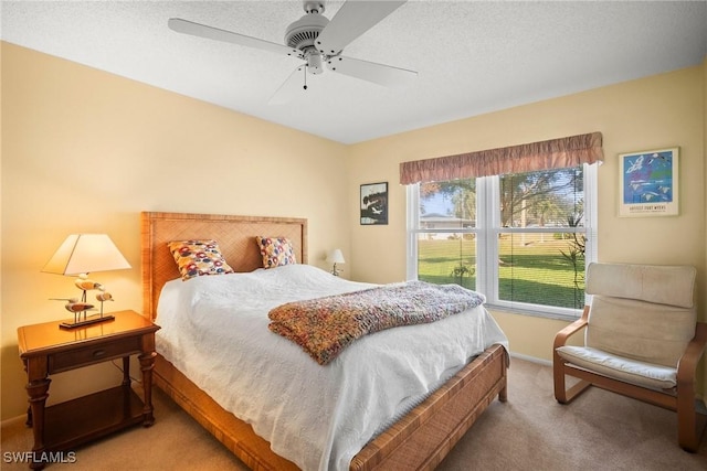 carpeted bedroom featuring ceiling fan and a textured ceiling