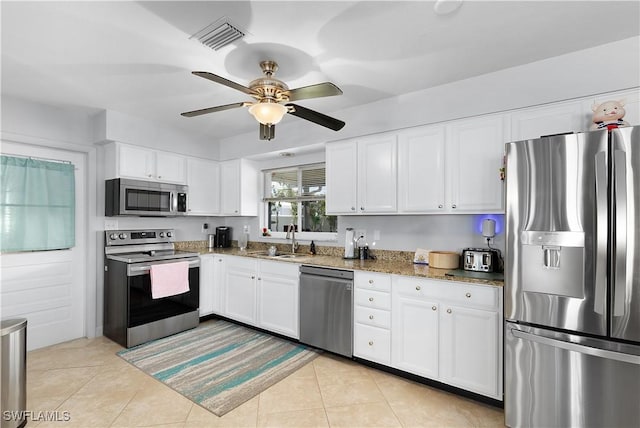 kitchen with sink, stone counters, stainless steel appliances, white cabinets, and light tile patterned flooring