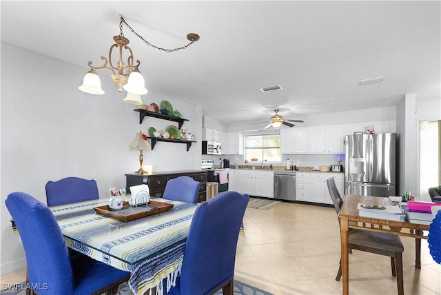 dining room with sink, ceiling fan with notable chandelier, and light tile patterned floors