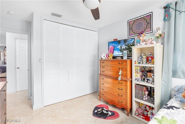 tiled bedroom with ceiling fan and a closet