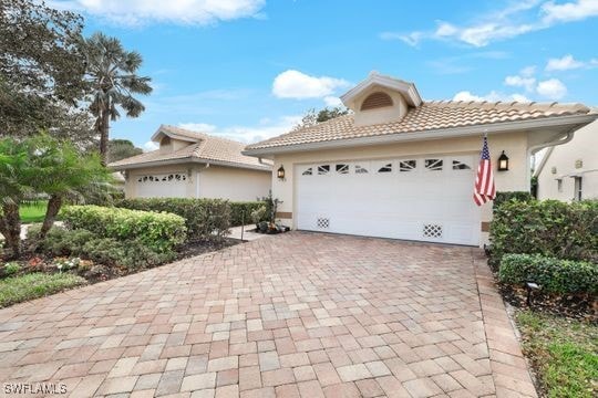 view of front of house featuring a tiled roof, decorative driveway, and stucco siding