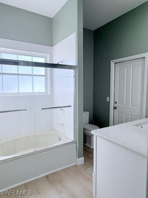 full bathroom with hardwood / wood-style flooring, enclosed tub / shower combo, vanity, and toilet