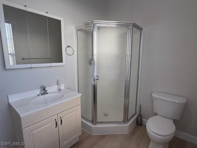 bathroom with vanity, hardwood / wood-style flooring, a shower with shower door, and toilet