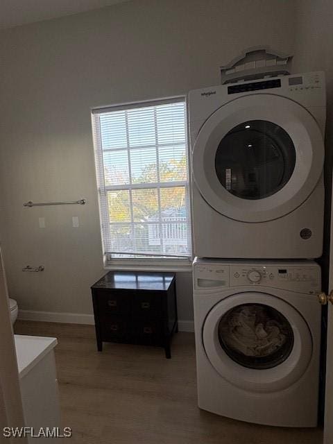 clothes washing area with stacked washer and dryer and light hardwood / wood-style floors