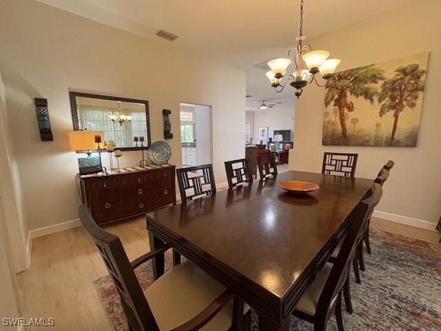 dining room featuring ceiling fan with notable chandelier and light hardwood / wood-style flooring