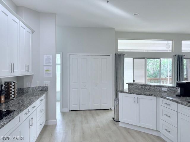 kitchen with dark stone countertops, light hardwood / wood-style flooring, and white cabinets